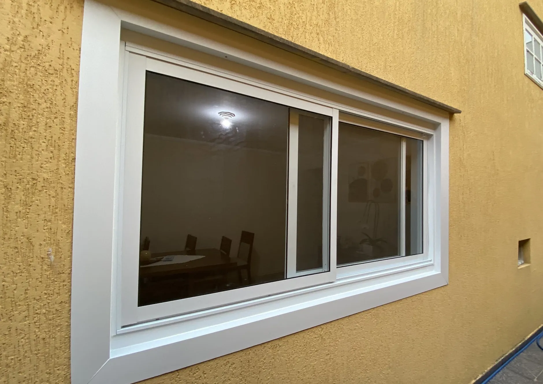 Janela de correr em alumínio branco na parede externa de uma casa